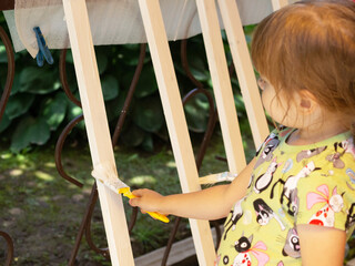 girl paints a wooden block with a brush