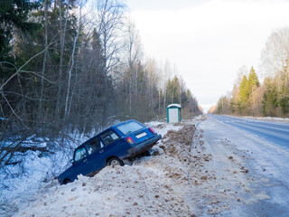 An abandoned car on the side of the road after a traffic accident. Symbolizes dangerous driving conditions in winter and icy conditions
