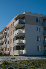 A sleek four-storey residential complex featuring a modern design, beige and gray tones, and elegant glass balconies for a contemporary urban feel.
