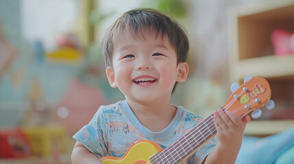 Happy smiling little asian boy playing plastic guitar instrument toy, male kid or child musician...