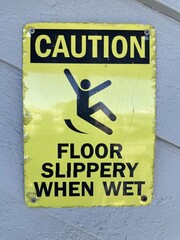A bright yellow and black sign that says caution floor slippery when wet.