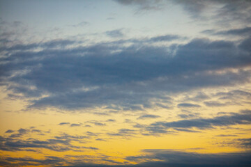 The peaceful and serene atmosphere of a cloudy sky at dusk is filled with warm hues of color