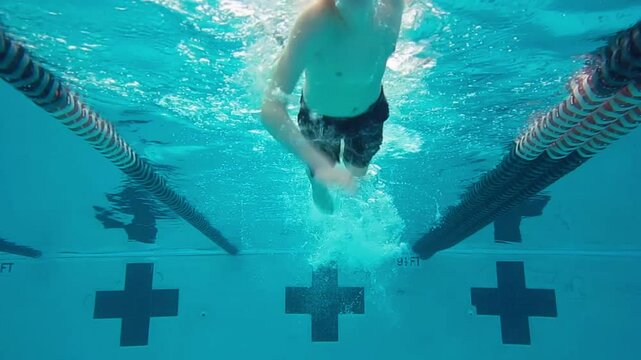 Underwater view of young boy swimming freestyle in pool.