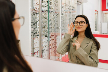 Woman tries and choose eyeglasses at optician corner in the shopping mall. Choosing eye glasses...