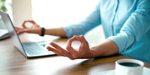 Unrecognizable Arab guy meditating in front of laptop pc, making gyan mudra with both hands, trying to keep calm at workplace, closeup. Stress management, work life balance concept