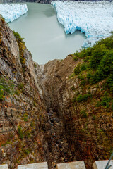 A wooden walkway high above a rocky gorge leading to glaciers floating in a lake, Grey Glacier and Lago Grey, Patagonia, Chile. 