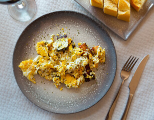 Fresh portion of fried eggs with pork pieces served on plate in restaurant