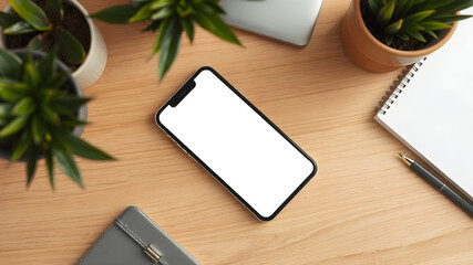 a composition of a smartphone on an office table with pens, notes, business graphs and a cup of coffee, display of tablet is turned on and showing a white blank background
