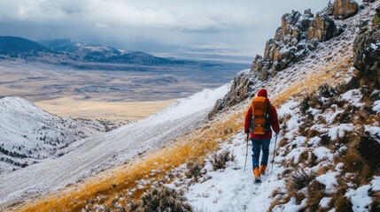 Naklejka premium Hiker ascends snowy mountain trail overlooking vast valley.