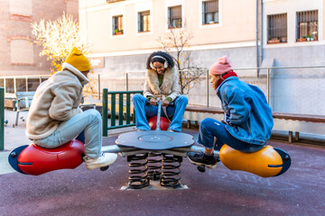 Friends playing on seesaw in city park during winter day