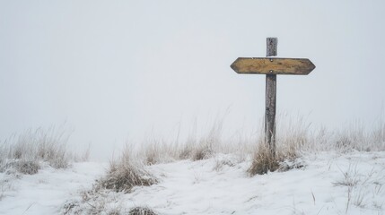 Naklejka premium A wooden signpost stands solitary on a snow-covered hill.