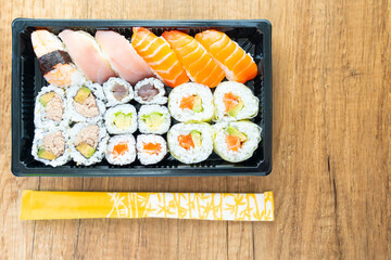 Japanese sushi combo tray delivery of exotic oriental food at home. Sushi tray assorted colorful healthy raw fish with chopsticks. A tray of assorted sushi with chopsticks.