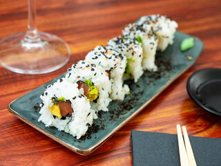 Uramaki. California salmon roll on wooden background. Salmon, avocado, rice, sesame. Japanese menu concept.