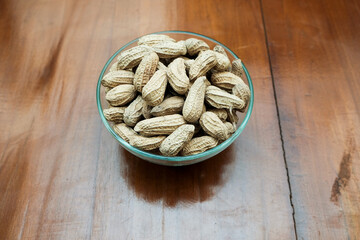 Organic Raw Peanuts in a glass Bowl on the wooden table, healthy snack