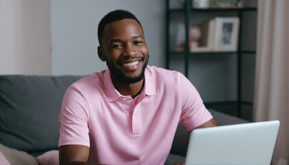 Young man working productively on laptop at home while smiling in casual attire during daytime