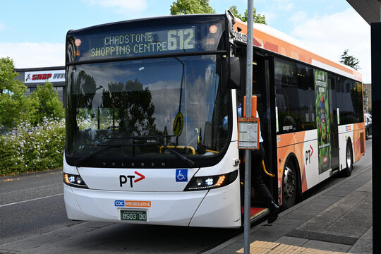 Front view of Scania K310UB bus, with hazard lights on, parked at a bus stop as the driver boards while obscured by bus stop signage