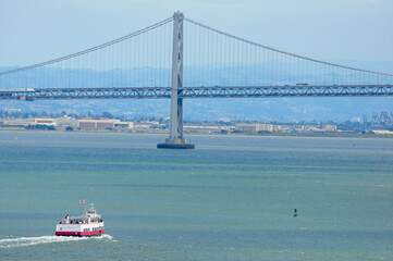 San Francisco, CA, USA. April 24, 2012: A scenic view of the San Francisco Bay Bridge with a ferry boat in the water below.