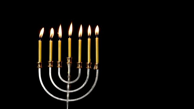 Hanukkah menorah with burning candles on black background. Jewish symbol.