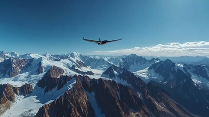 Fototapeta na wymiar A drone flying over majestic snow-capped mountains under a clear blue sky.