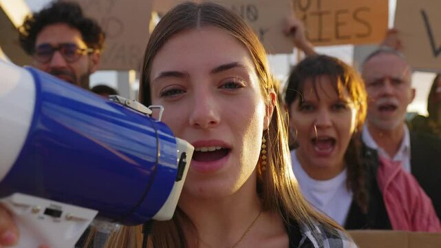 Group of diverse people manifesting against war or attack on a country. Female activist leading a demonstration using megaphone outdoors. Stop war signs and banners in a peace demonstration - Powered by Adobe