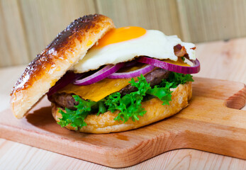 Tasty hamburger with with fried egg, beef, onion, cheese and lettuce