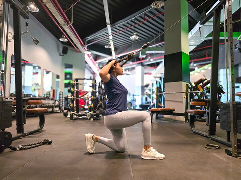 40 year old asian woman exercising for shoulder muscles with cable gym machine. Fitness training in the gym.