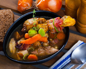 Picture of cooked tasty soup of chicken, bacon and leek, served in bowl at table