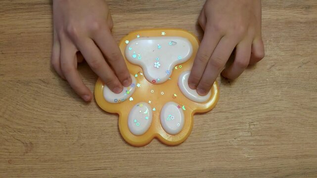 Young girls hands playing with taba paw yellow colorful toy antistress squish 