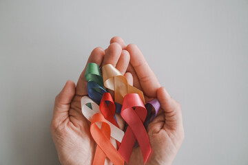 Hands holding color ribbons, world cancer day, World Autism Awareness Day concept