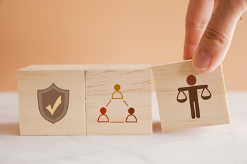 Hand holding wooden block with Ethical icons, business ethics and corporate compliance concept