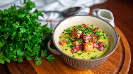 A comforting bowl of creamy pea soup topped with bacon, croutons, and fresh parsley.
