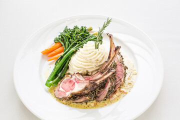 A plate of lamb chops with mashed potatoes and vegetables