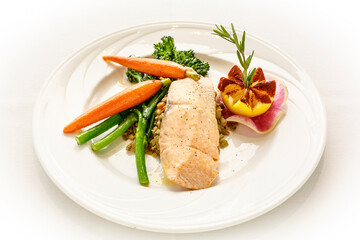 A plate of food with a piece of salmon, carrots, and green beans