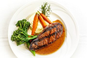 A plate of food with a steak, carrots, and broccoli