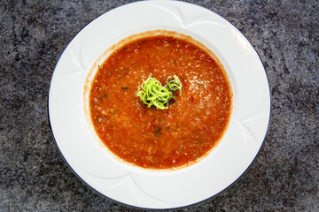 A bowl of soup with a green herb on top