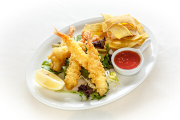A plate of food with shrimp, a lemon wedge, and a dipping sauce