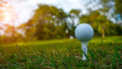 Golf ball on tee in a beautiful golf course with morning sunshine.