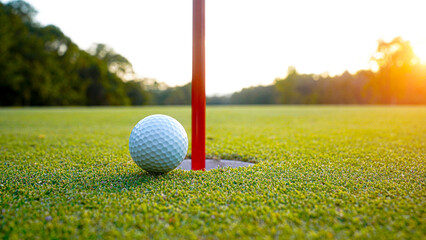 Golf ball is on a green lawn in a beautiful golf course with morning sunshine.