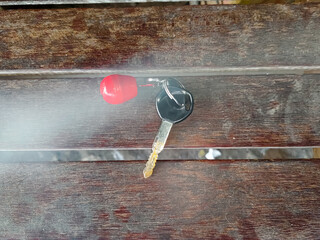 a key with a red wooden keychain on a bench with a natural smoke effect