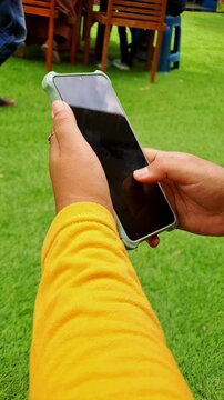 A woman in a vibrant yellow dress scrolls through her smartphone, capturing the essence of modern life and digital connection. Perfect for lifestyle videos, social media content, and tech