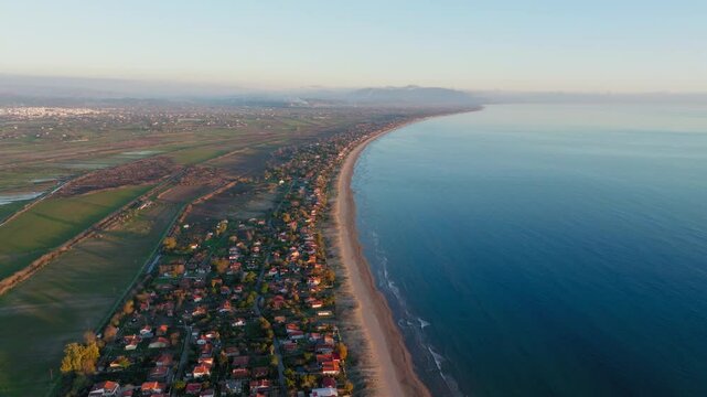 Aerial: Panoramic view of Spiantza beach and the arbitrary houses near the sea during sunset