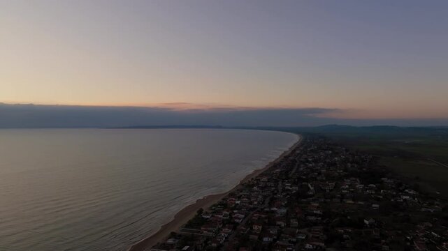 Aerial: Panoramic view of Letrina beach and the arbitrary houses near the sea during sunset
