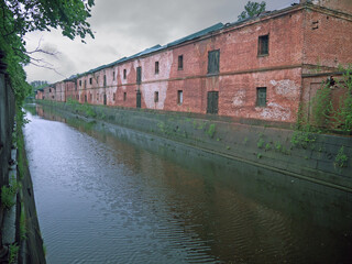 Long red brick wall and moat canal with water in Kronstadt fortress