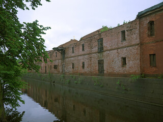 Long red brick wall and moat canal with water in Kronstadt fortress