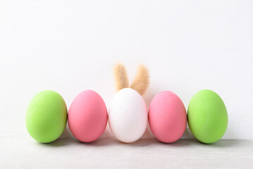 White easter eggs with bunny rabbit ears and colorful easter eggs on white background