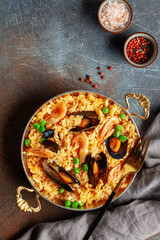 Traditional spanish seafood paella with rice, mussels, shrimps in a pan on concrete background. Top view. Flat lay
