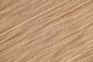 Texture of crumpled linen fabric under natural light in peach fuzz color