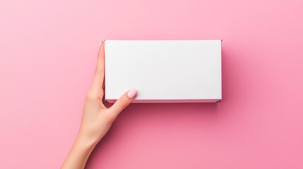 120.A neatly manicured female hand holding a blank, rectangular white cardboard box against a bold pink background, the boxâ€™s clean lines and simplicity accentuated by gentle shadows, making it