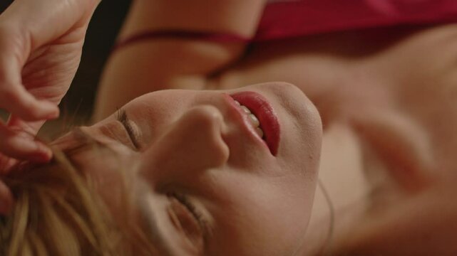 Extreme close up of a sensual woman lying on the floor and seductively smiling at the camera while playing with her hair