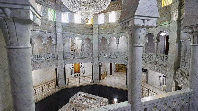 Central hall and interior of mausoleum of Habiba, Tunisia. Tomb of president is decorated with white marble, columns, and tiles. In center of first floor there is tomb and throne